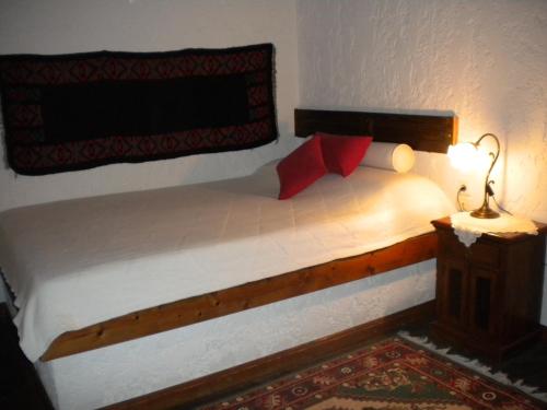 a bed with red pillows and a lamp in a bedroom at Agrampeli in Méga Khoríon