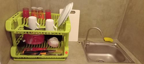 a green dish rack with utensils next to a sink at The Nest in Weligama