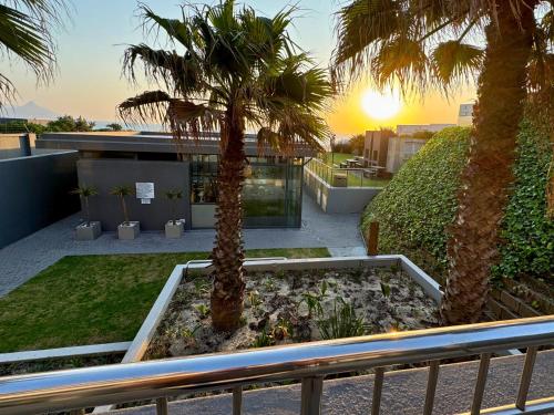 a view of a building with palm trees on a balcony at Infinity - Stunning 1 bedroom apartment with sea & mountain views in Bloubergstrand