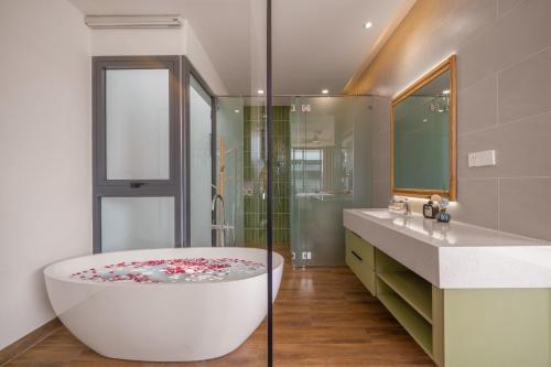 a bathroom with a tub and a glass shower at Amazing Newly Built Beach Pool Villas Danang in Da Nang