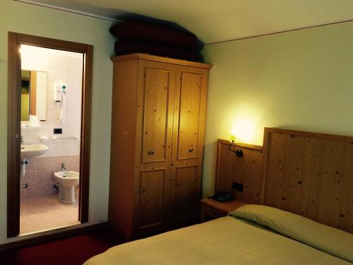 a bedroom with a bed and a bathroom with a sink at Hotel Ristorante Miramonti in Val Masino