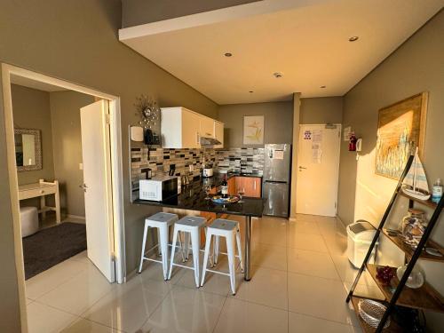a kitchen with a counter and stools in it at Infinity - Stunning 1 bedroom apartment with sea & mountain views in Bloubergstrand