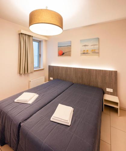 a bedroom with a blue bed with two towels at Vayamundo Oostende in Ostend