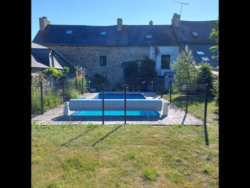 une piscine derrière une clôture en face d'une maison dans l'établissement L'Aberma - Maison à la campagne au fil de l'eau, à Saint-Lormel