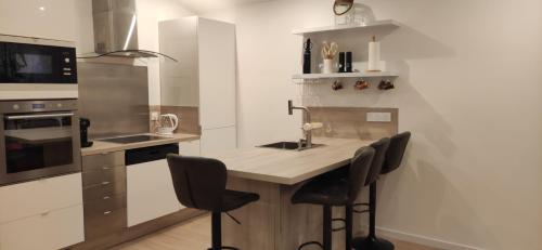 une cuisine avec un comptoir avec des chaises et un évier dans l'établissement Maison d'hôtes Coeur d'Hérault - Gîte et Chambres d'hôtes - SPA & Massages, à Péret
