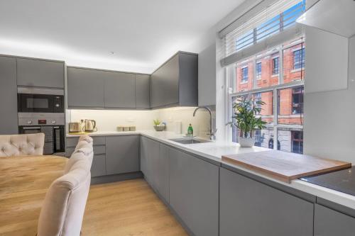 a kitchen with white cabinets and a large window at The Jade Suite - The Jewellery Suites, 3 bed 3 bath in Birmingham