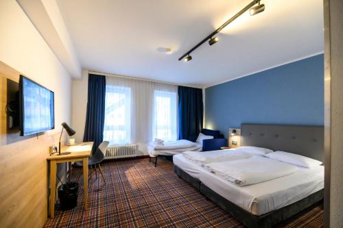 a hotel room with a large bed and a desk at Hotel Ambassador Essen in Essen
