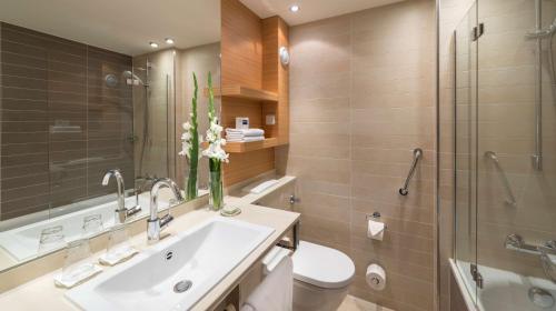 a bathroom with a sink and a toilet and a shower at Dorint Thermenhotel Freiburg in Freiburg im Breisgau