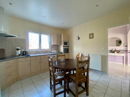 a kitchen with a table and chairs in a kitchen at Family Home - Aux portes de l'Histoire in Tour-en-Bessin