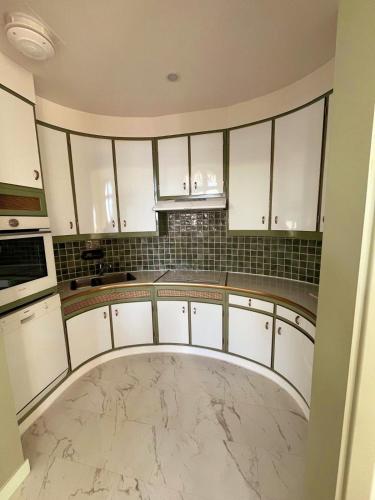 - une cuisine avec des placards blancs et un sol en marbre dans l'établissement Appartement 4 couchages vue mer Parc Continental, à Cannes