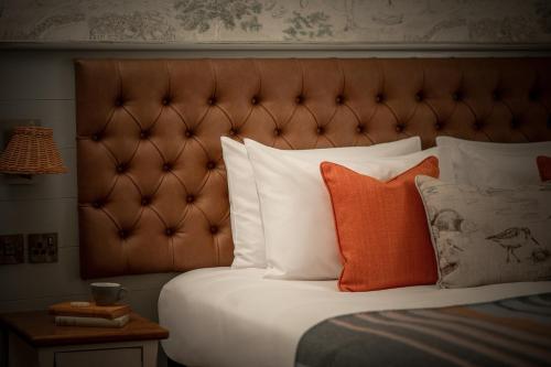 a bed with orange and white pillows and a headboard at The Royal Heysham in Heysham
