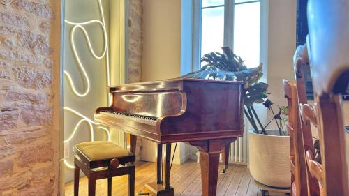 a piano in a room with a plant and a window at La Casa Do - Havre de Paix au Bord de L'eau in Cuisery