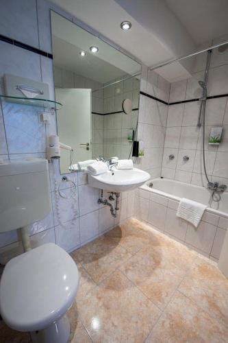 a bathroom with a toilet and a sink and a tub at PANORAMA HOTEL in Neustadt an der Weinstraße in Neustadt an der Weinstraße