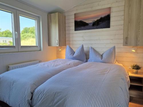 a large white bed in a bedroom with two windows at Ostseeferienpark Walkyrien - Kapitän 22 in Schashagen