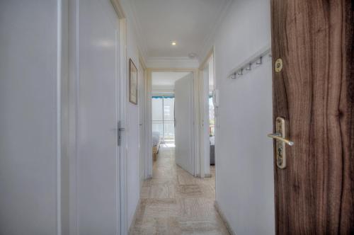 un couloir avec des murs blancs et une porte en bois dans l'établissement Immogroom - cosy apartment - Terrace - AC - Wifi, à Cannes