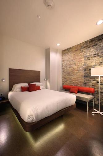a bedroom with a large bed and a brick wall at CityFlatsHotel - Grand Rapids, an Ascend Collection Hotel in Grand Rapids