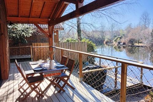 a table and chairs on a deck with a view of a river at Wooden lodge with garden in Vielle-Saint-Girons