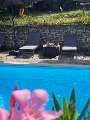 deux chaises et une table à côté d'une piscine dans l'établissement Le relais des clefs -Piscine chauffée, pétanque - 8pers, à Valpuiseaux