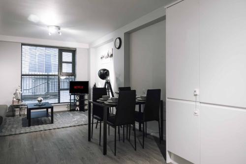 a living room with a table and chairs and a clock at Luxury 2 Bedroom Apartment near Stratford Station for Corporate and Group Stays in London