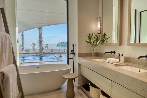bagno con vasca e lavandino con vista di Hawar Resort By Mantis a Hawar Island