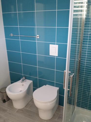 a blue tiled bathroom with a toilet and a shower at Le Castella B&B Restaurant in Le Castella