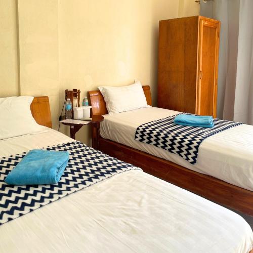 two beds in a small room withacers at Gold View Beachfront Resort in Timbaon