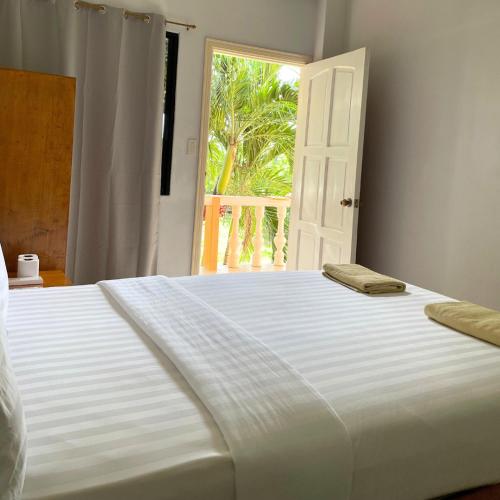 a large white bed in a room with a window at Gold View Beachfront Resort in Timbaon