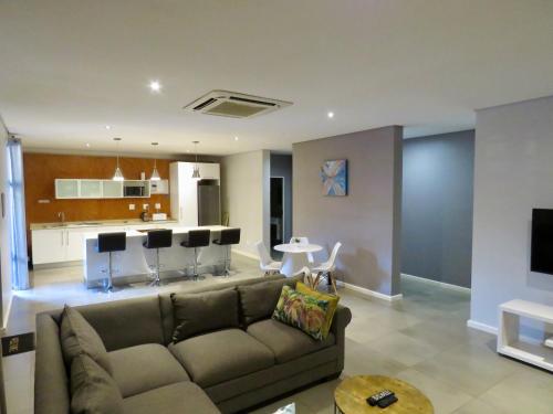 a living room with a couch and a kitchen at The Executive - Exclusive Self-Catering Apartments - Ezulwini in Ezulwini