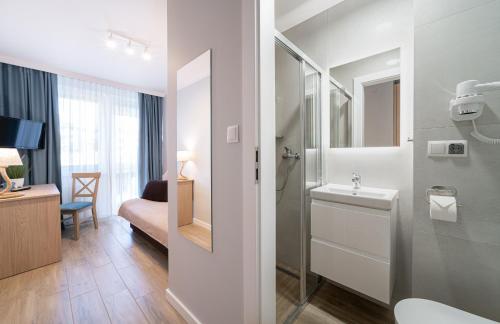 a bathroom with a sink and a toilet and a mirror at Resort Dankar in Dziwnów