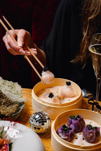 a person holding chopsticks over a table with food at Hart Shoreditch Hotel London, Curio Collection by Hilton in London