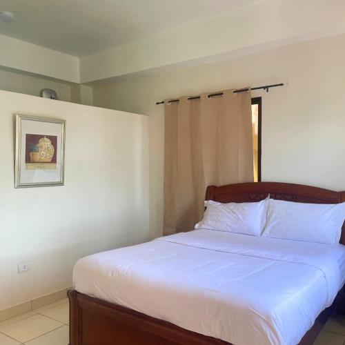 a bedroom with a bed with white sheets and a window at Gold View Beachfront Resort in Timbaon
