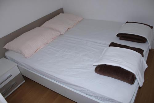 a bed with white sheets and brown pillows on it at Rab From Above Studio Apartment in Rab