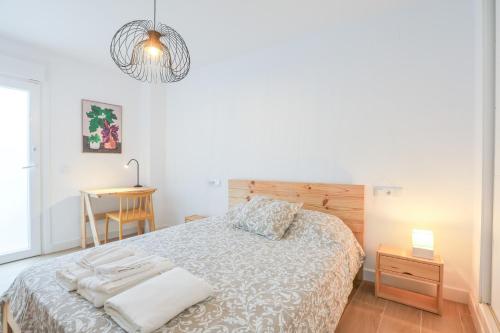 a white bedroom with a bed and a table at Delfin -Punta Umbria- in Punta Umbría