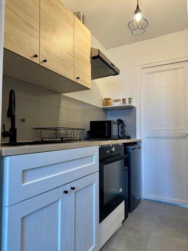 une cuisine avec des armoires blanches et un four à plaques de cuisson dans l'établissement Douce parenthèse, à Carcassonne