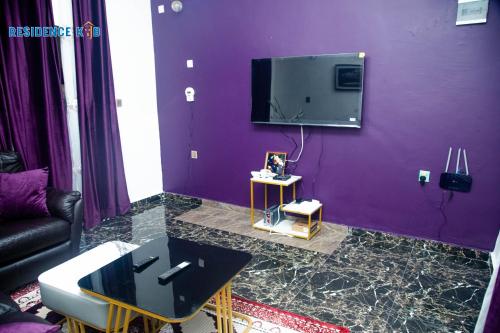 Una sala de estar morada con un televisor en una pared morada. en Residence kjb, en Yaoundé
