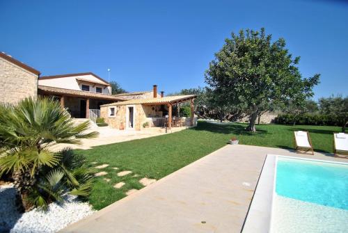 un patio con una casa y una piscina en Casa Natia - IsulaTravel, en Módica