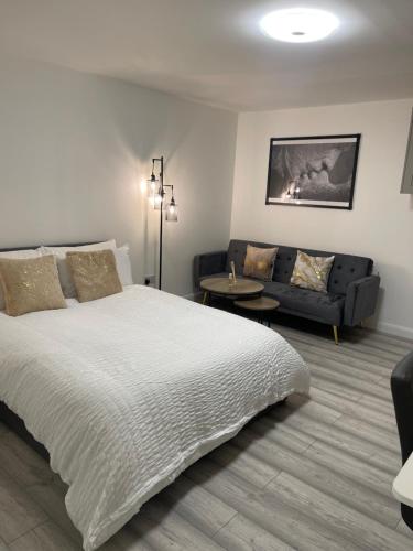 a bedroom with a white bed and a couch at Crown's Court in Orpington