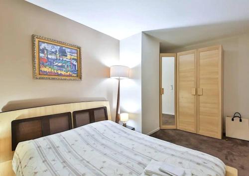 une chambre avec un grand lit et un tableau au mur dans l'établissement L'appartement Thibaud, à Paris