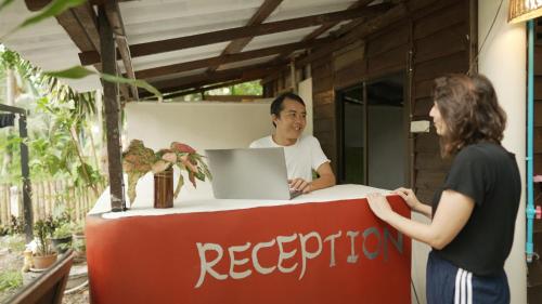 un hombre y una mujer parados en una recepción con un portátil en MY HOME Resort - Koh phangan vacation house rentals, en Ban Madua Wan