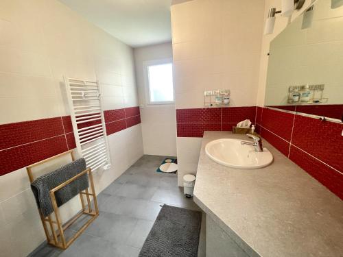La salle de bains est pourvue d'un lavabo et de carrelage rouge et blanc. dans l'établissement Le Mas des lavandes, à Saint-Gilles-Croix-de-Vie