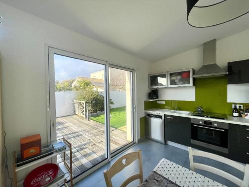 une cuisine avec une grande porte coulissante en verre s'ouvrant sur une terrasse. dans l'établissement Le Mas des lavandes, à Saint-Gilles-Croix-de-Vie