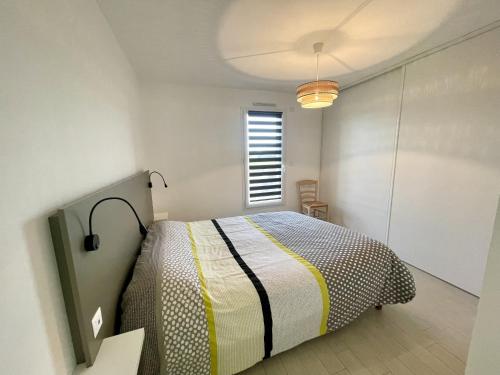 une chambre avec un lit dans une pièce blanche dans l'établissement Le Mas des lavandes, à Saint-Gilles-Croix-de-Vie