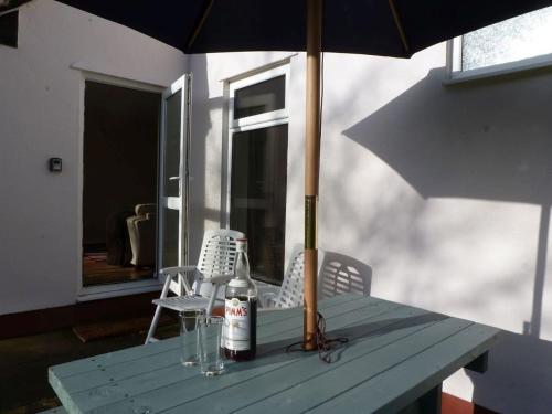 a blue table with an umbrella and two bottles and chairs at 8 Manorcombe Bungalows in Callington