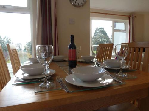 a dining room table with a bottle of wine and glasses at 8 Manorcombe Bungalows in Callington