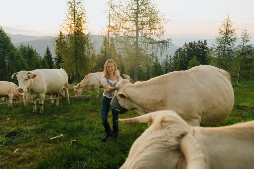 a woman standing in a field with a herd of cows at Glatz Hof Appartement Nockberge in Gnesau