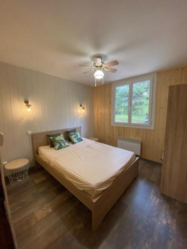 une chambre avec un lit et un ventilateur de plafond dans l'établissement Le Chalet des Berges - Piscine chauffée & Ponton Privé - En bordure de la rivière Aveyron, à Saint-Antonin