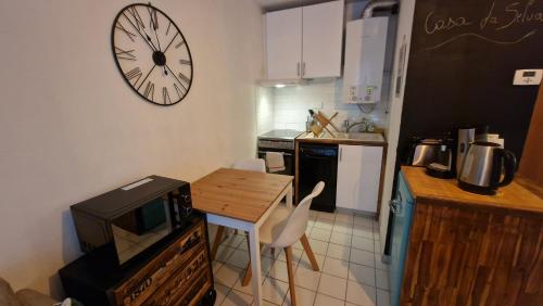 une cuisine avec une petite table et une horloge murale dans l'établissement Cosy appartement Beaux-Art à 5min du Corum, à Montpellier