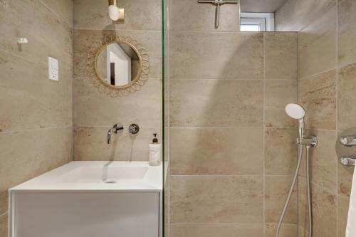 a bathroom with a shower with a sink and a mirror at Hørhavegården B&B in Højbjerg