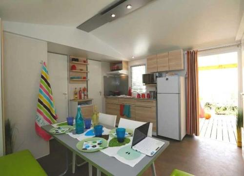- une cuisine avec une table et un ordinateur portable dans l'établissement Camping - Piscine - ccaggic, à Saint-Georges-dʼOléron
