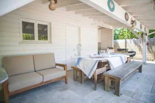 d'une terrasse avec une table, un banc et un évier. dans l'établissement Superbe villa de plage avec piscine chauffée et jacuzzi proche des plages, à La Teste-de-Buch